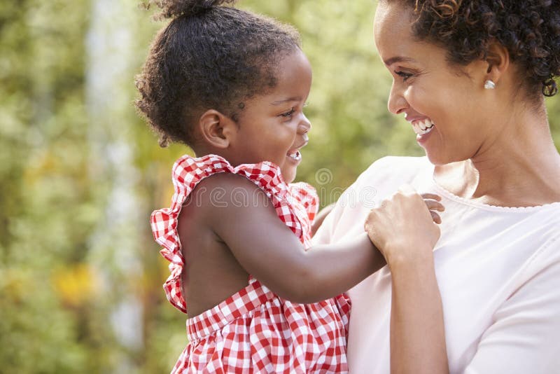La madre afroamericana lleva la hija del bebé y la mano de los controles imagen de archivo