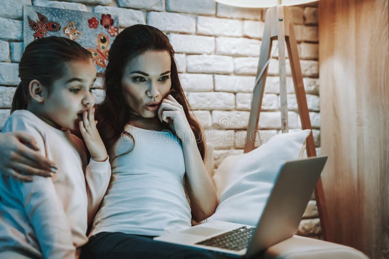 La madre con la hija está mirando un vídeo en el ordenador portátil imagen de archivo libre de regalías La madre con la hija está mirando un vídeo en el ordenador portátil imagen de archivo libre de regalías