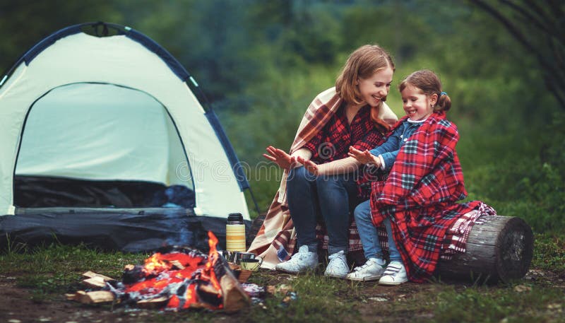 La madre della famiglia e la figlia del bambino riscaldano le loro mani dal falò sopra immagini stock libere da diritti La madre della famiglia e la figlia del bambino riscaldano le loro mani dal falò sopra immagini stock libere da diritti