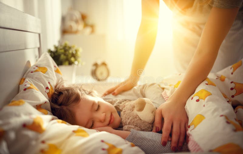 La madre despierta a la muchacha durmiente de la hija del niño por mañana foto de archivo libre de regalías La madre despierta a la muchacha durmiente de la hija del niño por mañana foto de archivo libre de regalías