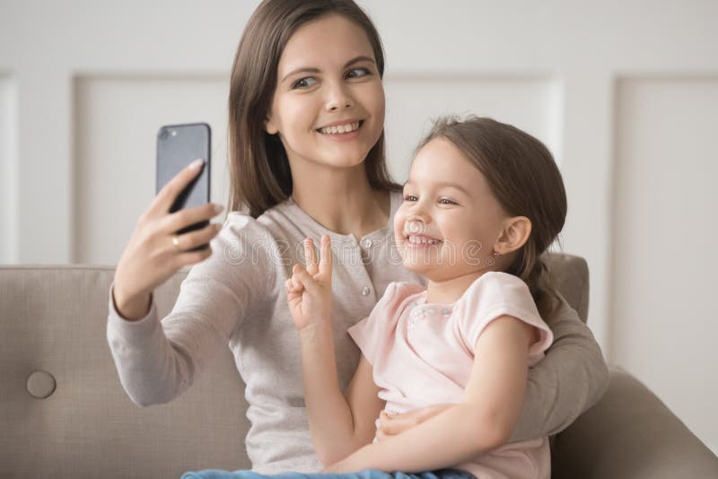 La madre divertente allegra tiene il selfie della presa dello smartphone con la figlia fotografia stock libera da diritti La madre divertente allegra tiene il selfie della presa dello smartphone con la figlia fotografia stock libera da diritti