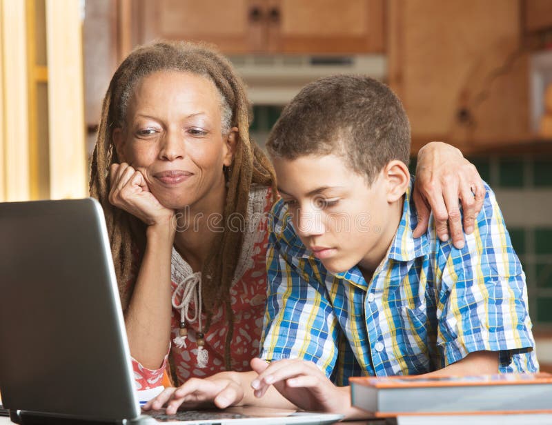 La madre ed il figlio teenager lavorano in cucina sul computer portatile