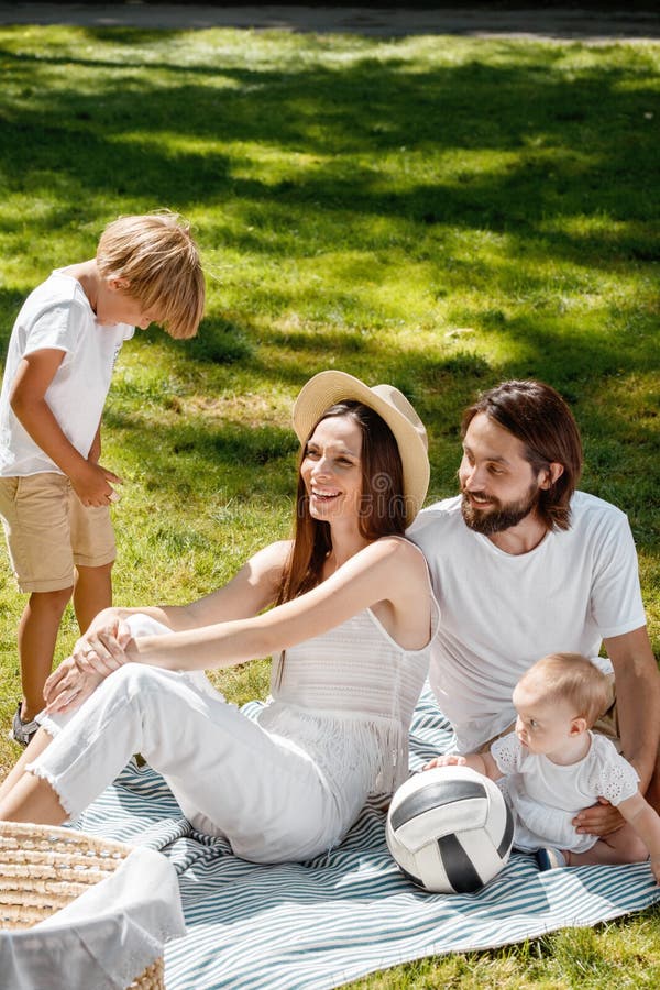 La Madre, El Padre, Su Hijo Y Poca Hija, Vestidos En La Ropa Blanca, Toman Resto En La Comida Campestre En El Parque Feliz Foto de archivo - Imagen de amor, mama: La Madre, El Padre, Su Hijo Y Poca Hija, Vestidos En La Ropa Blanca, Toman Resto En La Comida Campestre En El Parque Feliz Foto de archivo - Imagen de amor, mama: