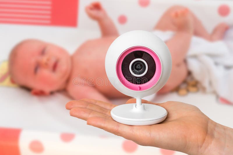 La madre está celebrando la cámara del monitor del bebé para la seguridad de su bebé foto de archivo libre de regalías La madre está celebrando la cámara del monitor del bebé para la seguridad de su bebé foto de archivo libre de regalías