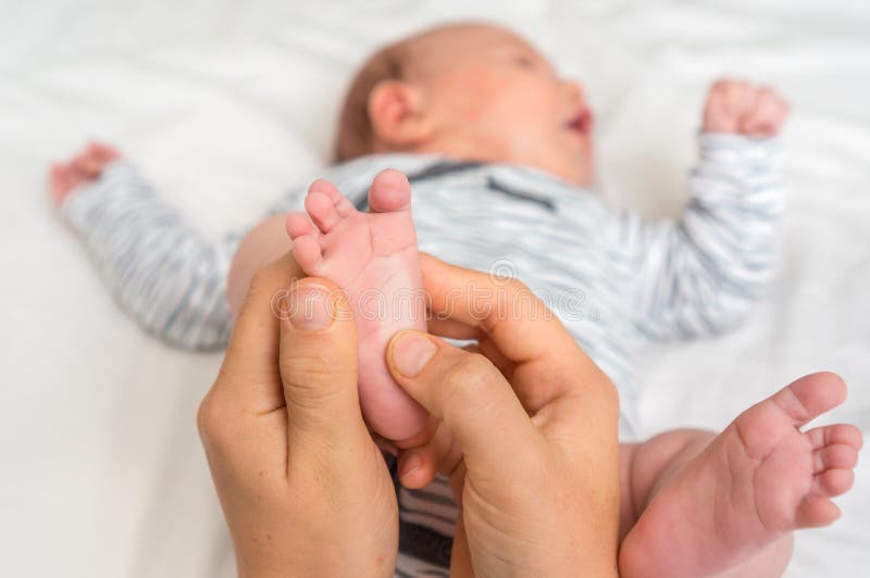 La madre fa il massaggio del piede per il suo bambino fotografia stock libera da diritti La madre fa il massaggio del piede per il suo bambino fotografia stock libera da diritti