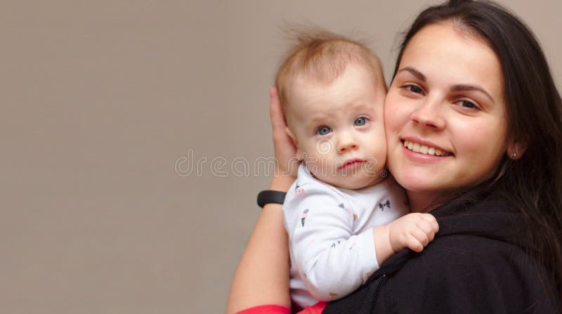 la madre joven celebra a su bebé divertido, dulce en sus brazos imagen de archivo la madre joven celebra a su bebé divertido, dulce en sus brazos imagen de archivo