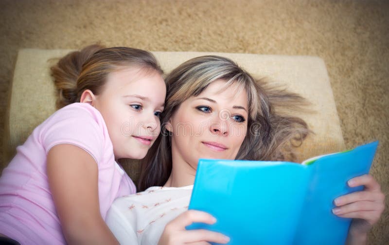La madre joven está leyendo un libro a su hija imagen de archivo libre de regalías La madre joven está leyendo un libro a su hija imagen de archivo libre de regalías