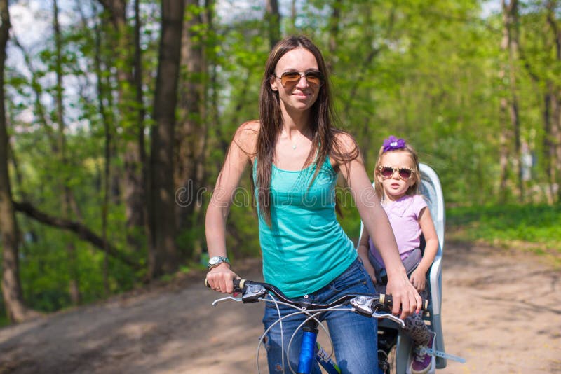 La madre joven y el pequeño montar a caballo lindo de la hija bikes juntos fotos de archivo libres de regalías La madre joven y el pequeño montar a caballo lindo de la hija bikes juntos fotos de archivo libres de regalías