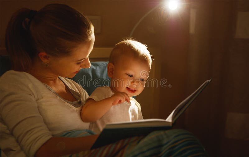 La madre lee al libro del bebé en cama fotografía de archivo libre de regalías La madre lee al libro del bebé en cama fotografía de archivo libre de regalías
