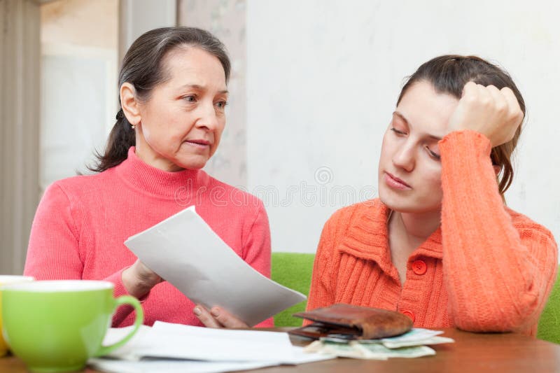 La madre madura regaña a la hija para las cuentas o los créditos foto de archivo La madre madura regaña a la hija para las cuentas o los créditos foto de archivo