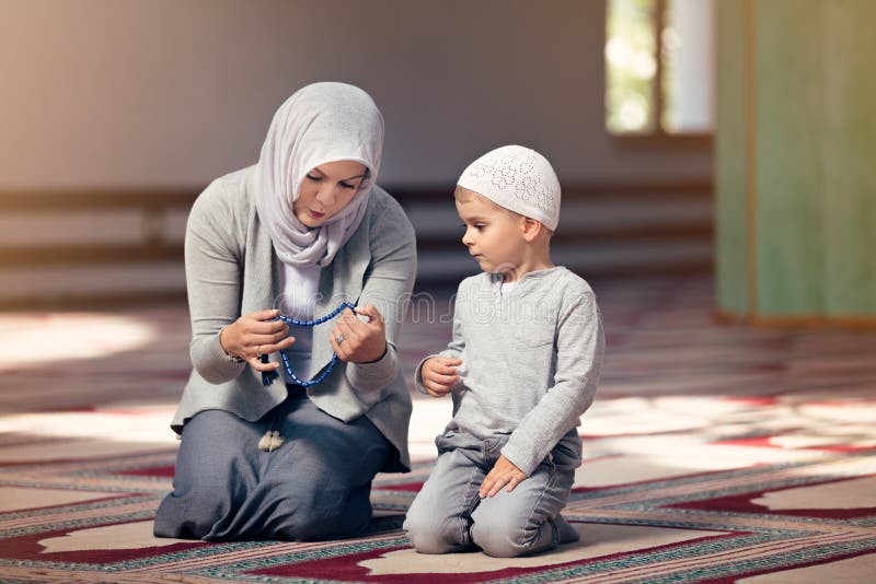La madre musulmana insegna a suo figlio che prega dentro la moschea fotografia stock libera da diritti La madre musulmana insegna a suo figlio che prega dentro la moschea fotografia stock libera da diritti