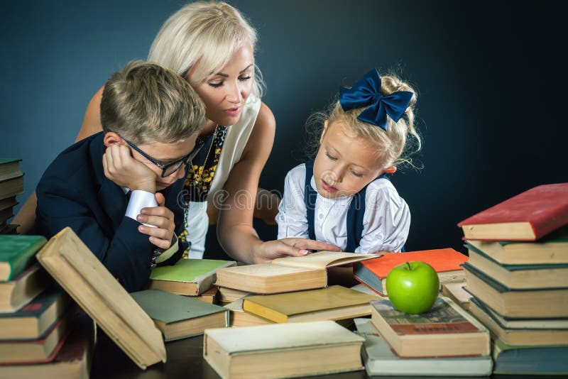 La madre o l'insegnante che aiuta per la scuola scherza fare il compito, leggente immagini stock libere da diritti La madre o l'insegnante che aiuta per la scuola scherza fare il compito, leggente immagini stock libere da diritti