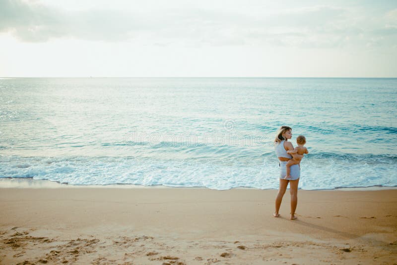 La madre porta il bambino sulla spiaggia fotografie stock libere da diritti La madre porta il bambino sulla spiaggia fotografie stock libere da diritti