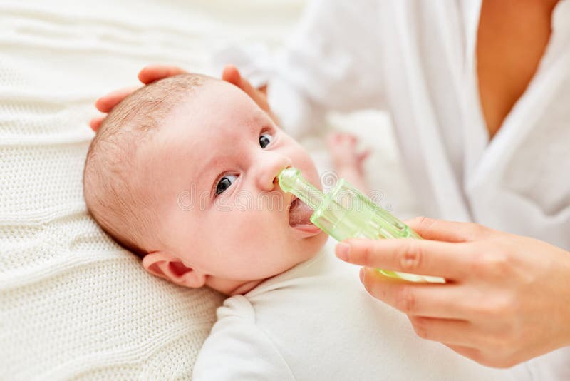 Mother cleans nose of little baby with a nasal aspirator for common cold. Mother cleans nose of little baby with a nasal aspirator for common cold