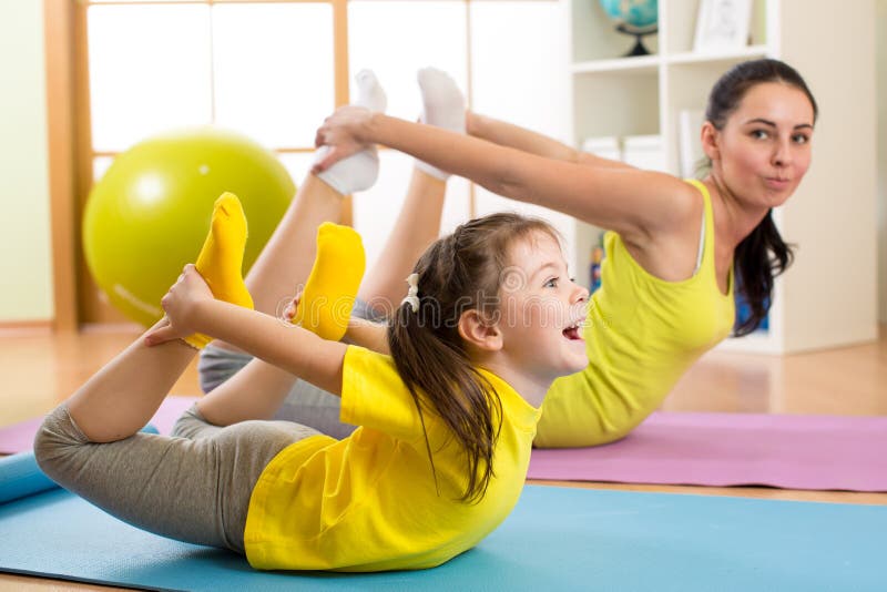 La madre y el niño en el gimnasio centran hacer estirando ejercicio de la aptitud Yoga
