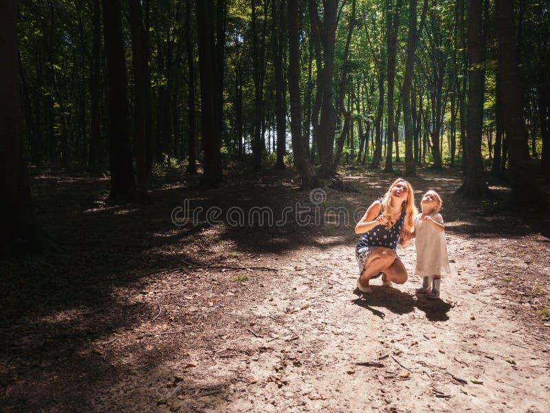 La madre y la niña en el sol se encienden dentro del bosque fotografía de archivo libre de regalías La madre y la niña en el sol se encienden dentro del bosque fotografía de archivo libre de regalías