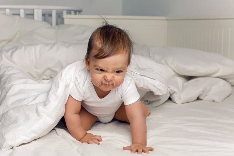 La maglietta del bambino del ragazzo si trova sotto una coperta fotografia stock La maglietta del bambino del ragazzo si trova sotto una coperta fotografia stock