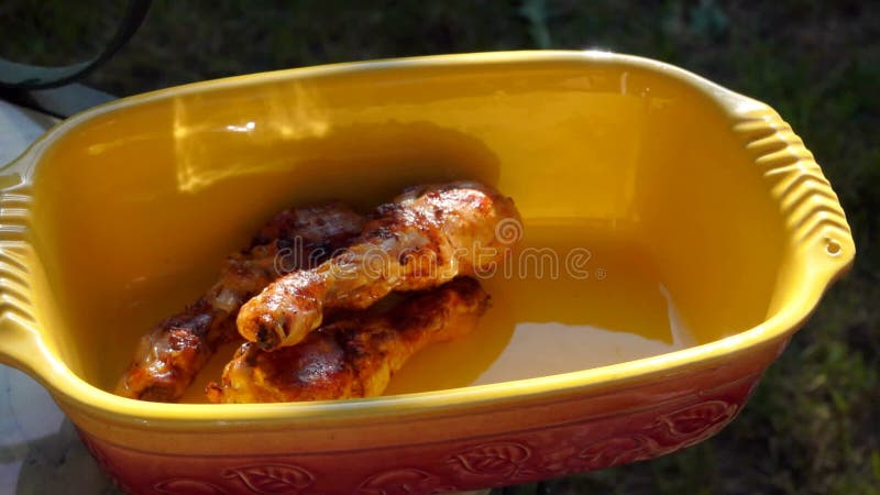 La main avec des pinces, a placé des jambes de poulet frit dans un plat en céramique banque de vidéos