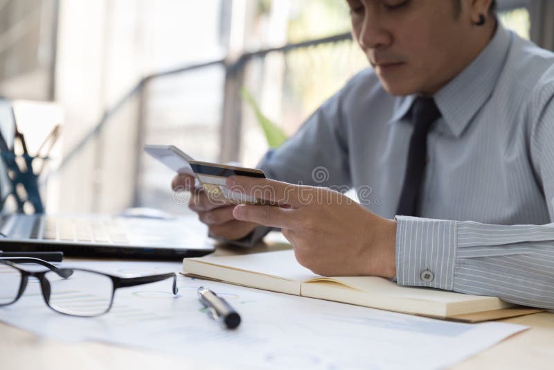 La main d'homme d'affaires jugeant une carte de crédit attentive a fait un p en ligne image libre de droits La main d'homme d'affaires jugeant une carte de crédit attentive a fait un p en ligne image libre de droits