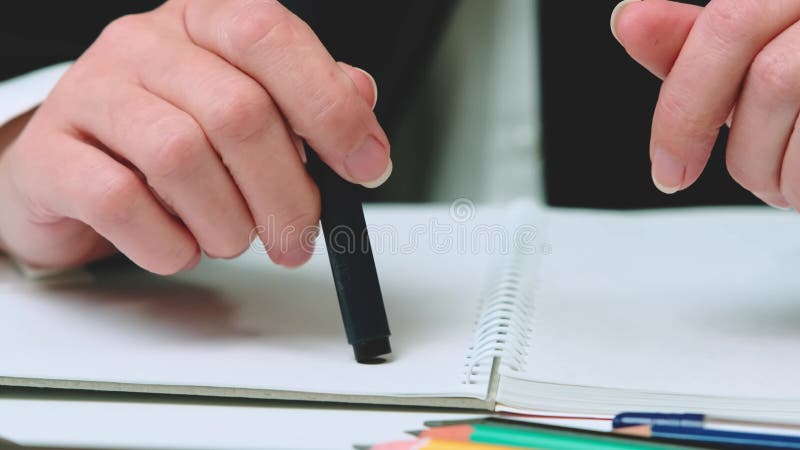 La main d'une femme d'affaires tient un stylo entre ses mains dans le bureau clips vidéos