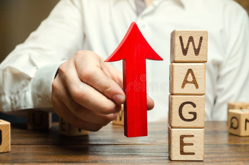Businessman`s hand holds red arrow up near wooden blocks with word Wage. Salary increase concept. Wages rate. Revenue growth and profits. Successful business. Career rise. Promote. Stability. Businessman`s hand holds red arrow up near wooden blocks with word Wage. Salary increase concept. Wages rate. Revenue growth and profits. Successful business. Career rise. Promote. Stability