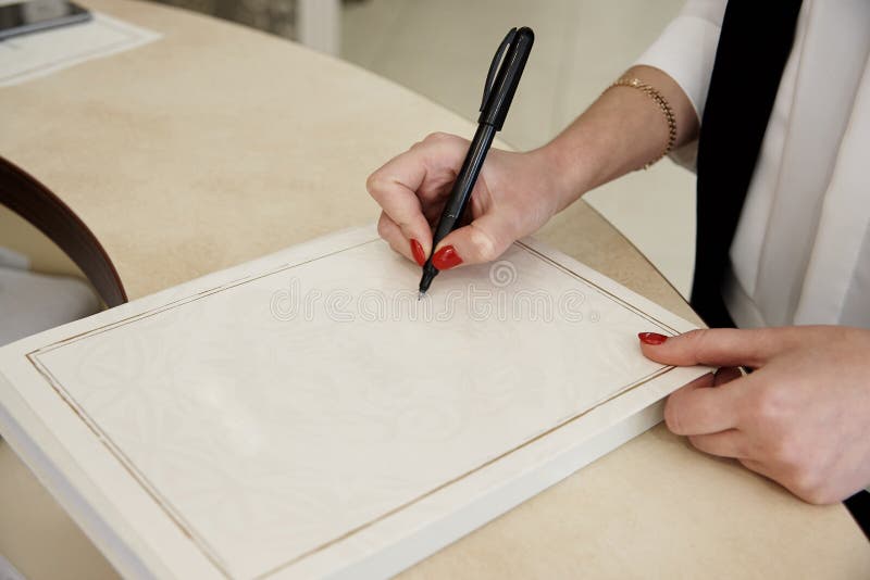 La main du ` s de fille tient un stylo sur la feuille de papier photographie stock La main du ` s de fille tient un stylo sur la feuille de papier photographie stock