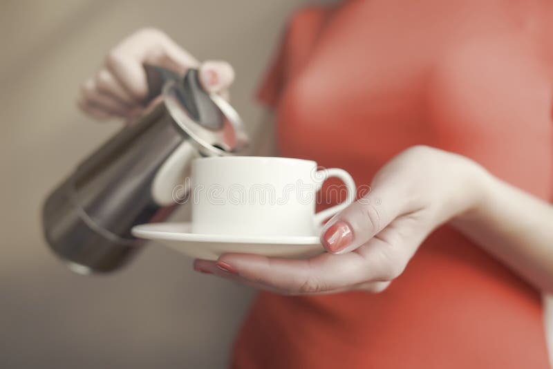La main femelle verse une boisson dans la tasse du fabricant de café photo libre de droits La main femelle verse une boisson dans la tasse du fabricant de café photo libre de droits