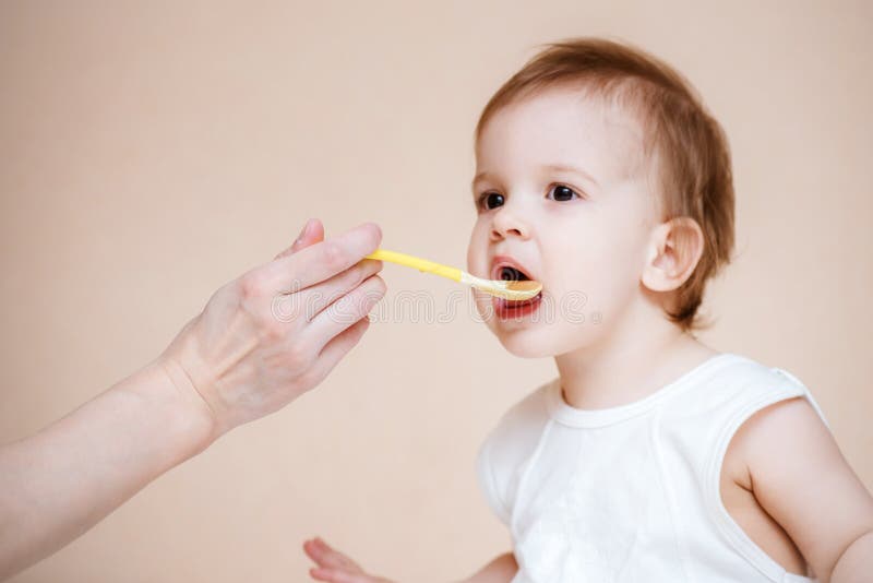 La maman alimente le bébé avec la purée de fruit images libres de droits La maman alimente le bébé avec la purée de fruit images libres de droits