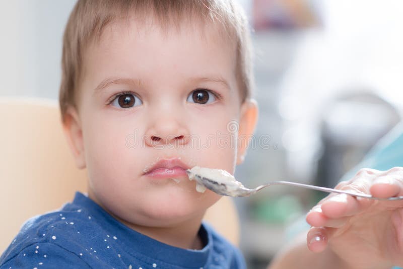 La maman alimente le gruau de sarrasin de bébé dans la cuisine images libres de droits La maman alimente le gruau de sarrasin de bébé dans la cuisine images libres de droits