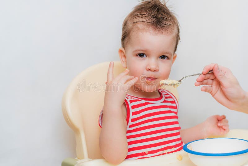 La maman alimente le gruau de sarrasin de bébé dans la cuisine photographie stock libre de droits La maman alimente le gruau de sarrasin de bébé dans la cuisine photographie stock libre de droits