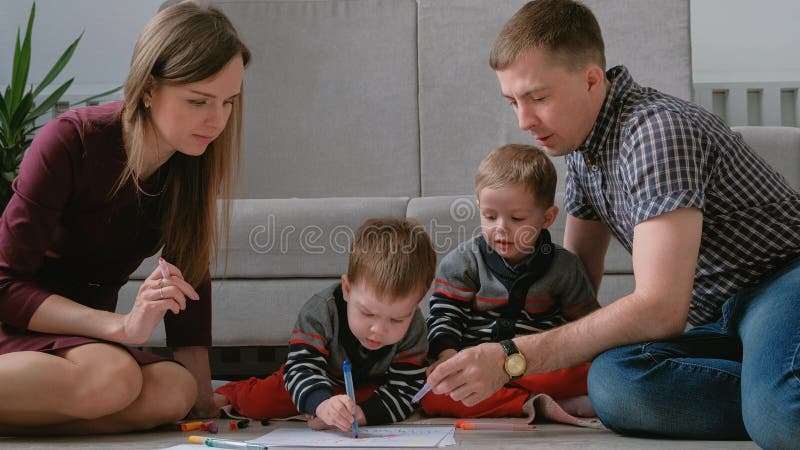 La maman de famille, le papa et deux frères jumeaux réunissent des marqueurs et ont senti des stylos se reposer sur le plancher images libres de droits La maman de famille, le papa et deux frères jumeaux réunissent des marqueurs et ont senti des stylos se reposer sur le plancher images libres de droits