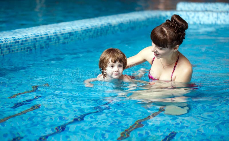 La maman enseigne un enfant ? nager dans la piscine photo stock La maman enseigne un enfant ? nager dans la piscine photo stock