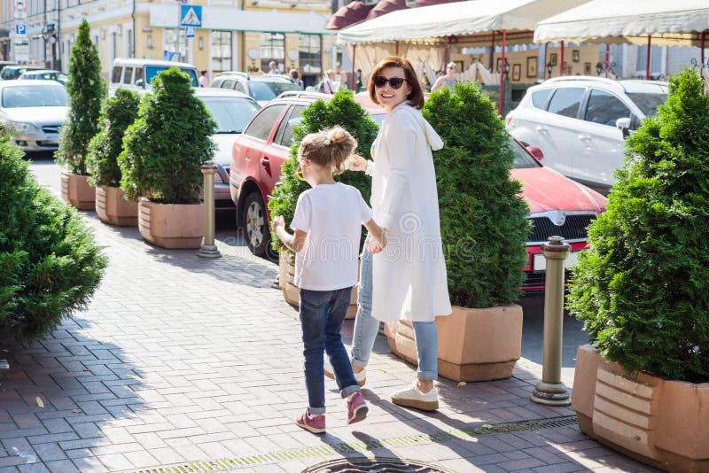 La maman et la fille tiennent des mains, marchant le long de la rue de ville photo stock La maman et la fille tiennent des mains, marchant le long de la rue de ville photo stock