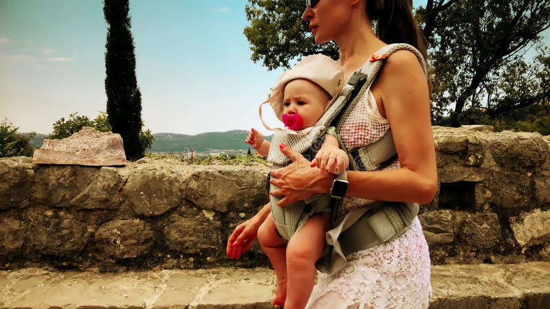 La maman et son enfant voyageant avec le transporteur de bébé se baladent des vacances
