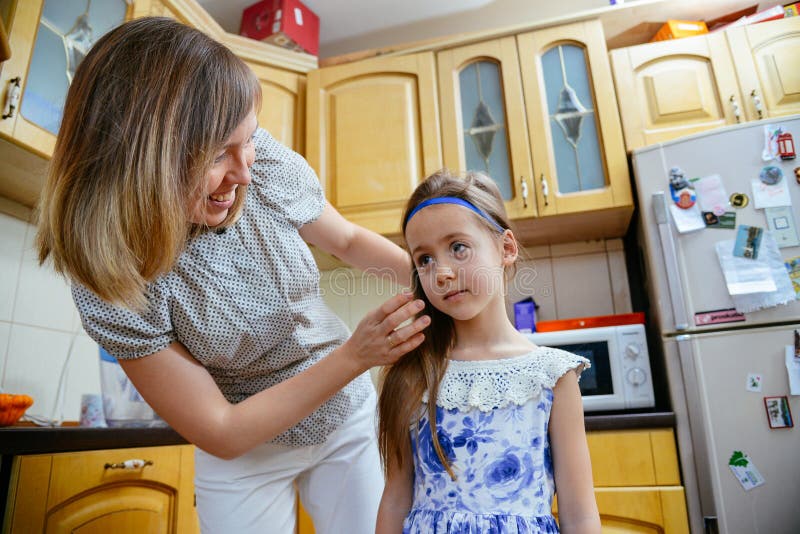 La maman fait la coiffure de fille dans le kithen image libre de droits La maman fait la coiffure de fille dans le kithen image libre de droits