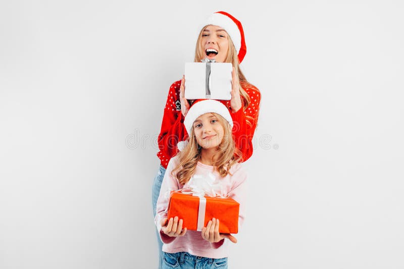 La mamma e la figlia felici celebrano il nuovo anno, nei cappelli di Santa e nello swe immagini stock La mamma e la figlia felici celebrano il nuovo anno, nei cappelli di Santa e nello swe immagini stock