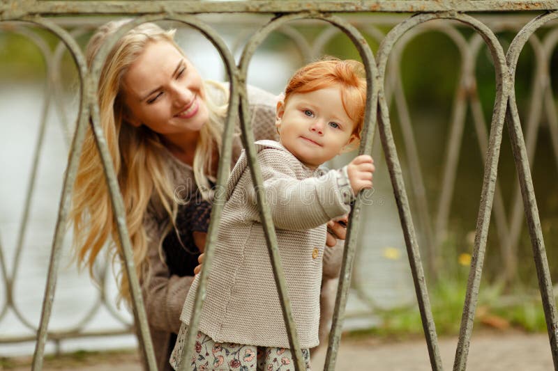 La mamma esamina la neonata dai capelli rossi e la risata, autunno immagine stock libera da diritti La mamma esamina la neonata dai capelli rossi e la risata, autunno immagine stock libera da diritti