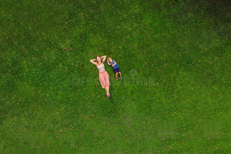 La mamá y el hijo están mintiendo en la hierba en el parque, fotos del abejón, quadracopter fotografía de archivo libre de regalías La mamá y el hijo están mintiendo en la hierba en el parque, fotos del abejón, quadracopter fotografía de archivo libre de regalías