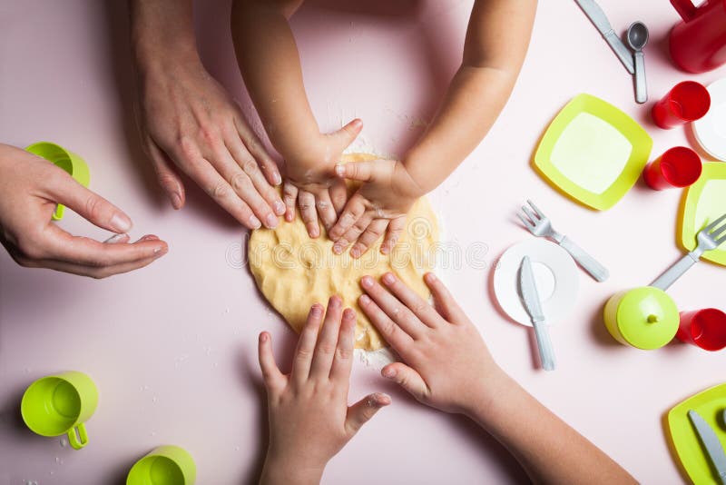 La mamá y los niños cuecen las galletas en la cocina y adornan las galletas el la Nochebuena, la visión superior fotografía de archivo La mamá y los niños cuecen las galletas en la cocina y adornan las galletas el la Nochebuena, la visión superior fotografía de archivo