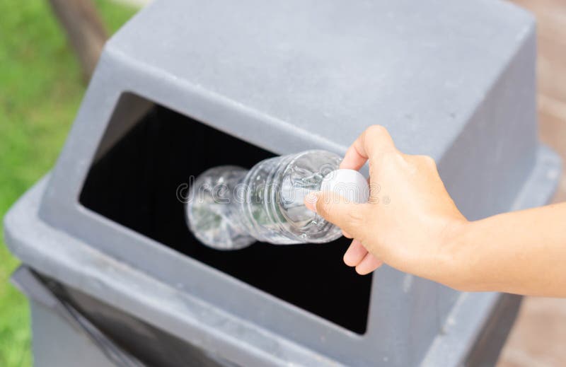 La mano alta vicina che tiene la bottiglia di plastica dell'immondizia in ricicla il bidone della spazzatura, fuoco selettivo immagine stock libera da diritti La mano alta vicina che tiene la bottiglia di plastica dell'immondizia in ricicla il bidone della spazzatura, fuoco selettivo immagine stock libera da diritti