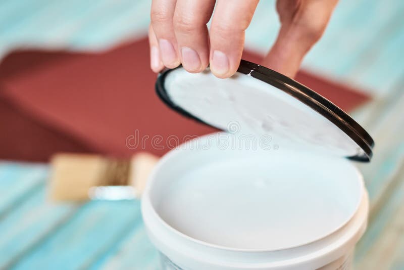 La mano apre una latta di pittura bianca e dei bordi di legno che preparano per dipingere fotografie stock libere da diritti La mano apre una latta di pittura bianca e dei bordi di legno che preparano per dipingere fotografie stock libere da diritti