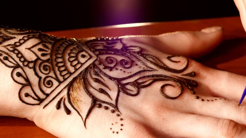 La mano de la mujer adornada con mehendi, en negro