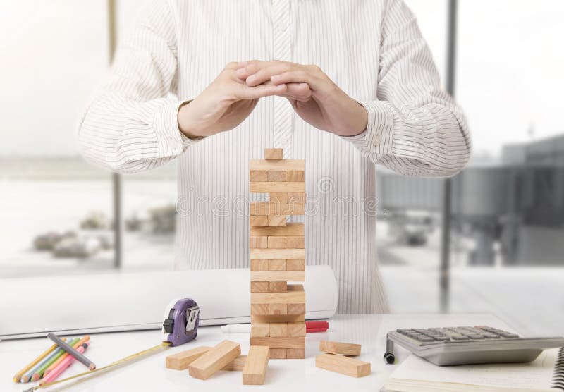 La mano de la protección del ingeniero bloquea el juego de madera de la torre imagen de archivo La mano de la protección del ingeniero bloquea el juego de madera de la torre imagen de archivo