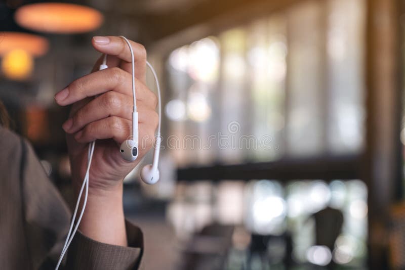 La mano de una mujer que sostiene los auriculares a escuchar la música imagen de archivo La mano de una mujer que sostiene los auriculares a escuchar la música imagen de archivo