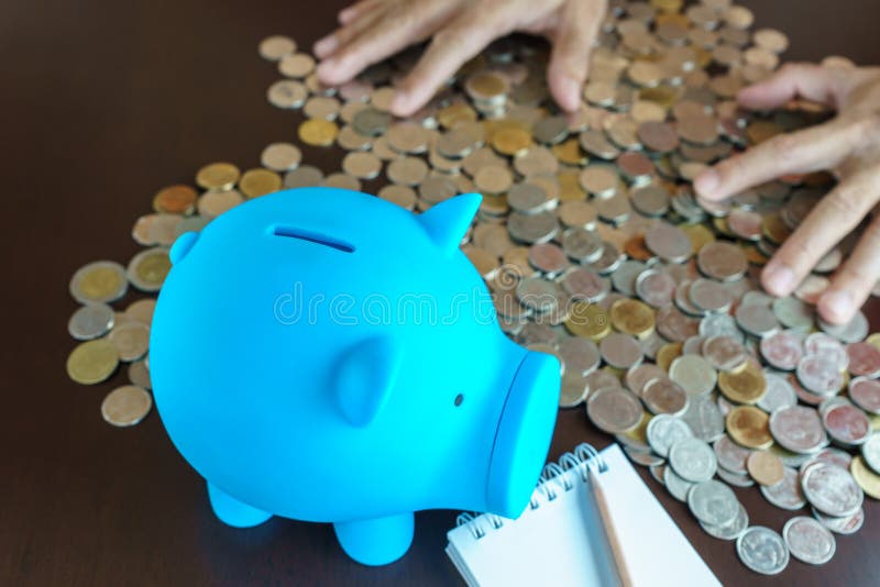 La mano del hombre recoge la moneda del dinero en la hucha azul fotografía de archivo La mano del hombre recoge la moneda del dinero en la hucha azul fotografía de archivo