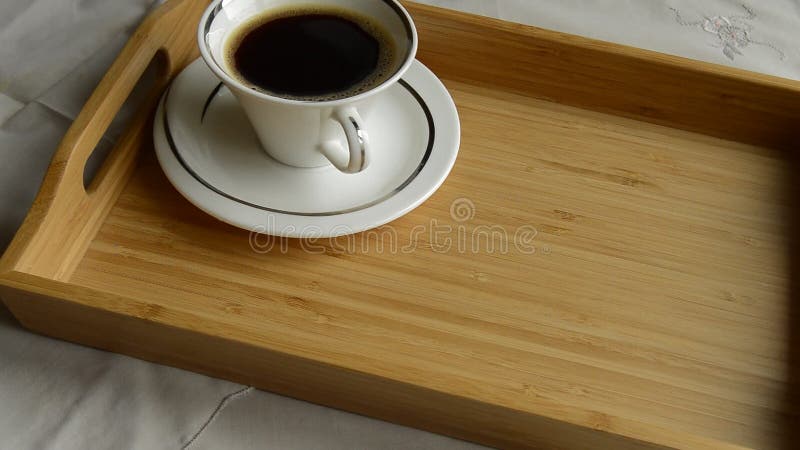 La mano del ` s della donna mette sopra il vassoio di legno una tazza di caffè e una torta di formaggio su un piatto