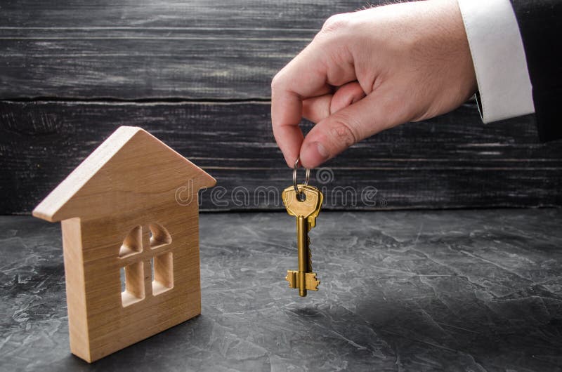 La mano del ` s di agente immobiliare tiene le chiavi alla casa Casa di legno Il concetto di acquisto e di vendita degli appartam immagini stock libere da diritti La mano del ` s di agente immobiliare tiene le chiavi alla casa Casa di legno Il concetto di acquisto e di vendita degli appartam immagini stock libere da diritti