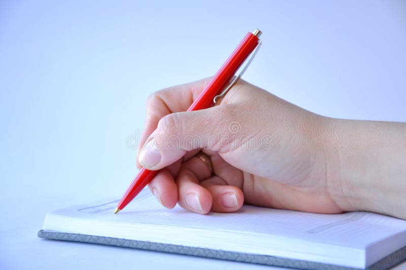 La mano dell'uomo che tiene una penna e che scrive in un taccuino fotografia stock La mano dell'uomo che tiene una penna e che scrive in un taccuino fotografia stock