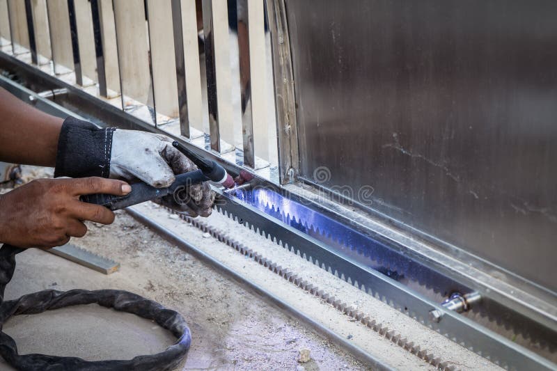 La mano dell'uomo del lavoratore che salda una struttura di porta di acciaio inossidabile dentro si batte fotografie stock libere da diritti La mano dell'uomo del lavoratore che salda una struttura di porta di acciaio inossidabile dentro si batte fotografie stock libere da diritti