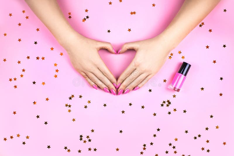 La mano della donna con il manicure di corallo che fa cuore immagini stock La mano della donna con il manicure di corallo che fa cuore immagini stock